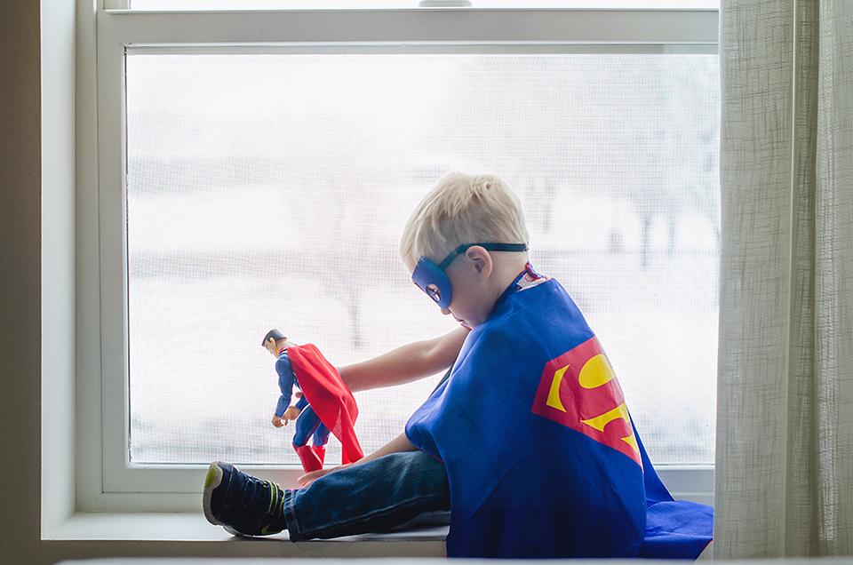 Junge mit Superman Kostüm spielt Superheldenfigur
